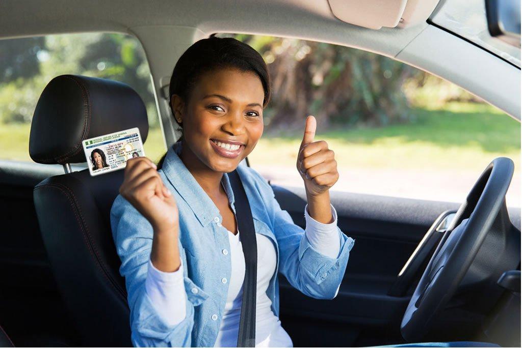 driver in car holding license with thumb up