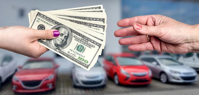 money exchanging hands, cars in background