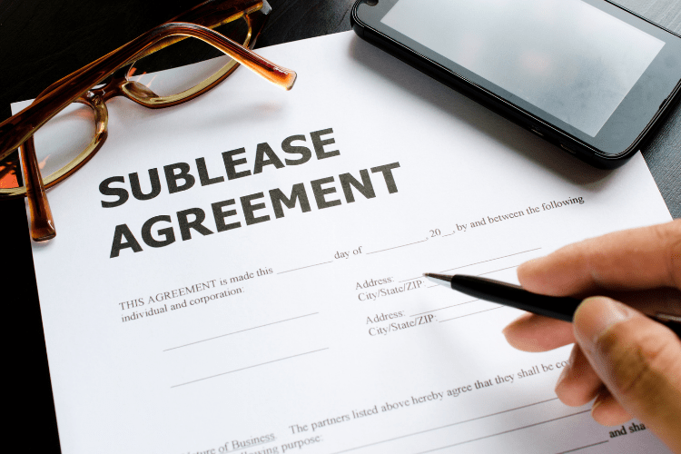 paper with sublease agreement printed at top, handing with pen
